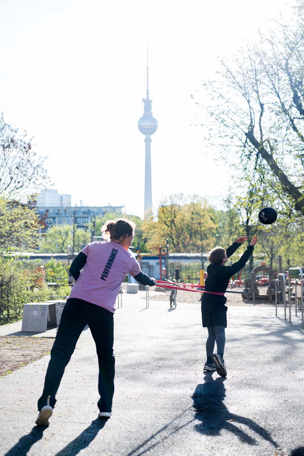 Coach Bibiane arbeitet mit einem Athleten an einer dynamischen Übung mit dem Medizinball, Fokus auf Kraft und Koordination.